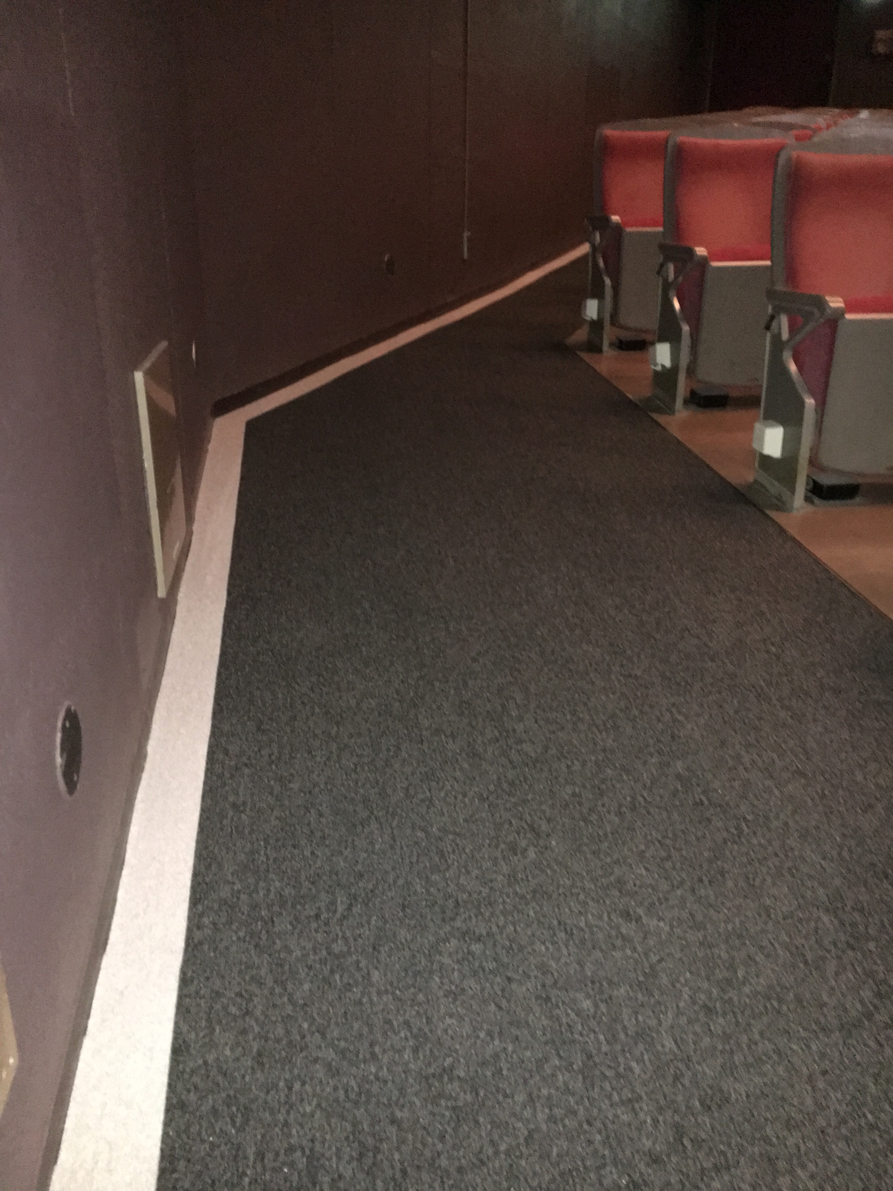 薄暗い客席内の床と壁の境目に太くて白い線が引いてある